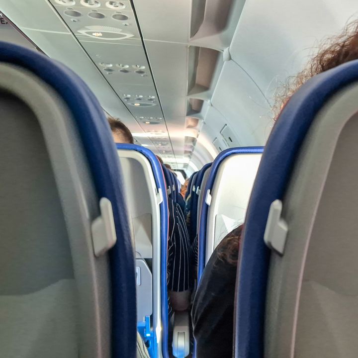 An eye-level view of rows of airplane seats filled with people.