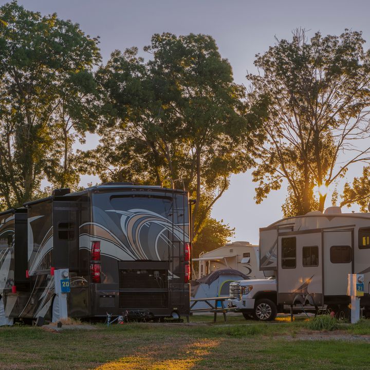 A bunch of RVs parked for camping at a resort at sunset.