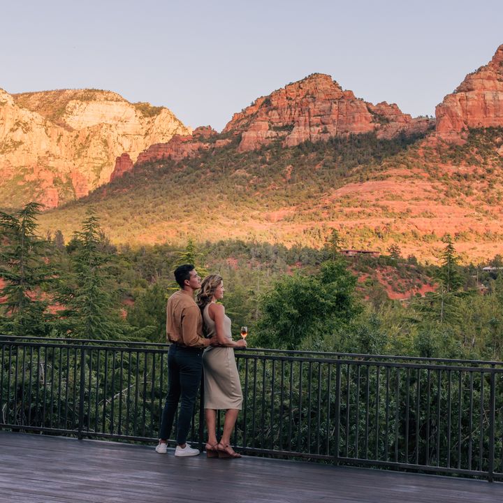 A man and a woman embracing while taking in views on a deck facing Sedona’s scenic red rock formations.