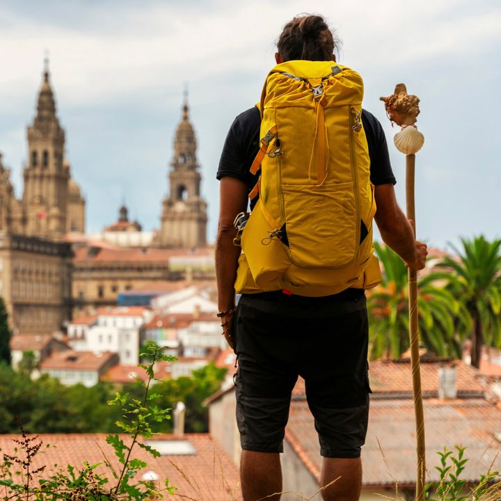 A pilgrim looking at the Cathedral of Santiago de Compostela in Spaink, backpack on his back.