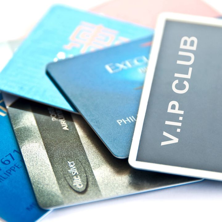 An array of travel and credit cards fanned out on a white table.