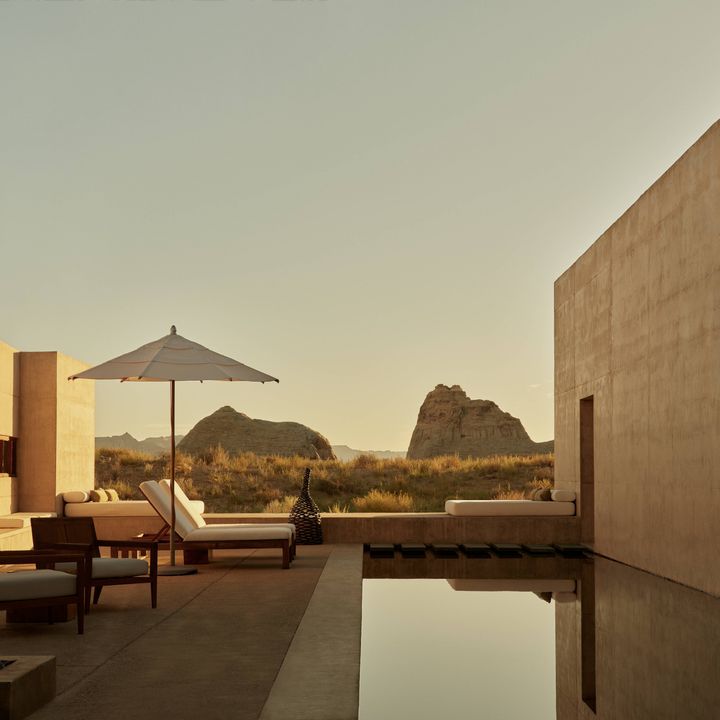 An outdoor terrace with a private pool overlooks sweeping desert scenery bathed in the golden light of sunset.