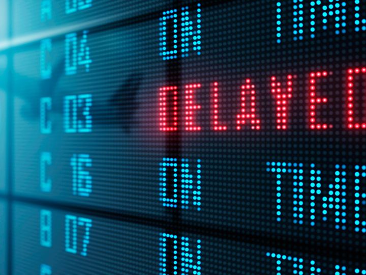 An airport LED board showing delayed and on-time flights