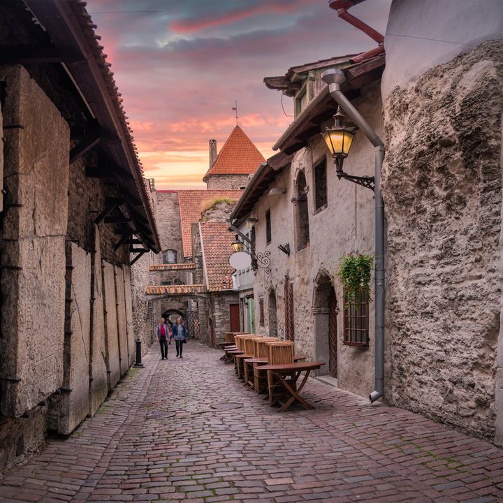 A narrow historic street in Old Town Tallinn, Estonia, with stone walls and cobblestone street.