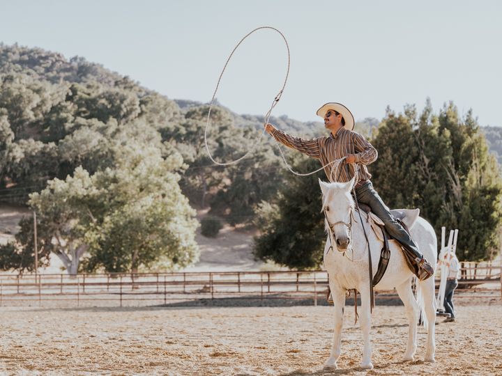 A man on a horse swinging a lasso into the air.