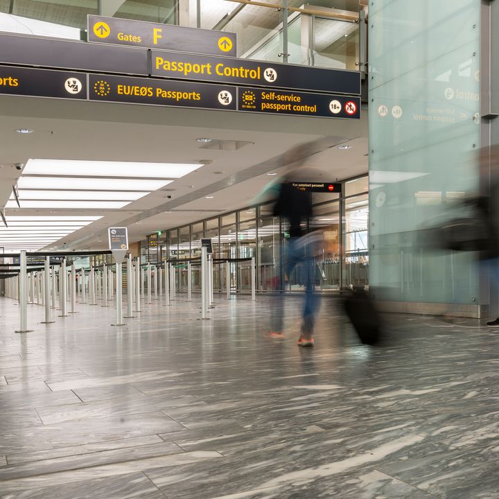 A passport control line area in an airport with a blurred-out tourist going through.