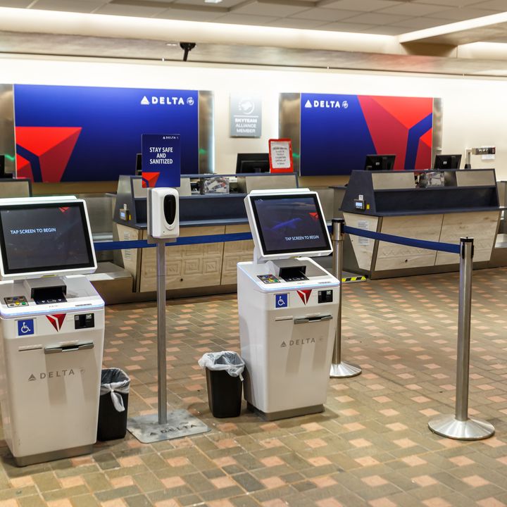 An empty Delta check-in area with kiosks and terminals to check luggage.